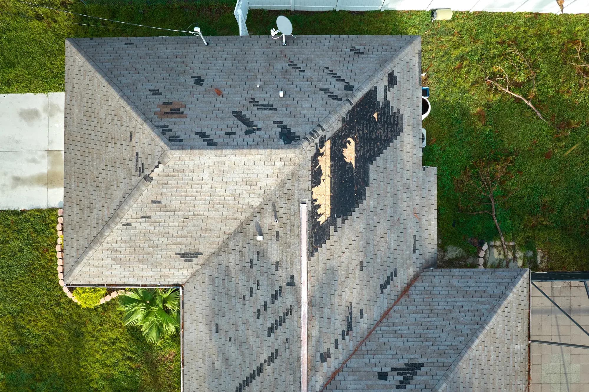 Aerial view of a storm-damaged roof with missing shingles