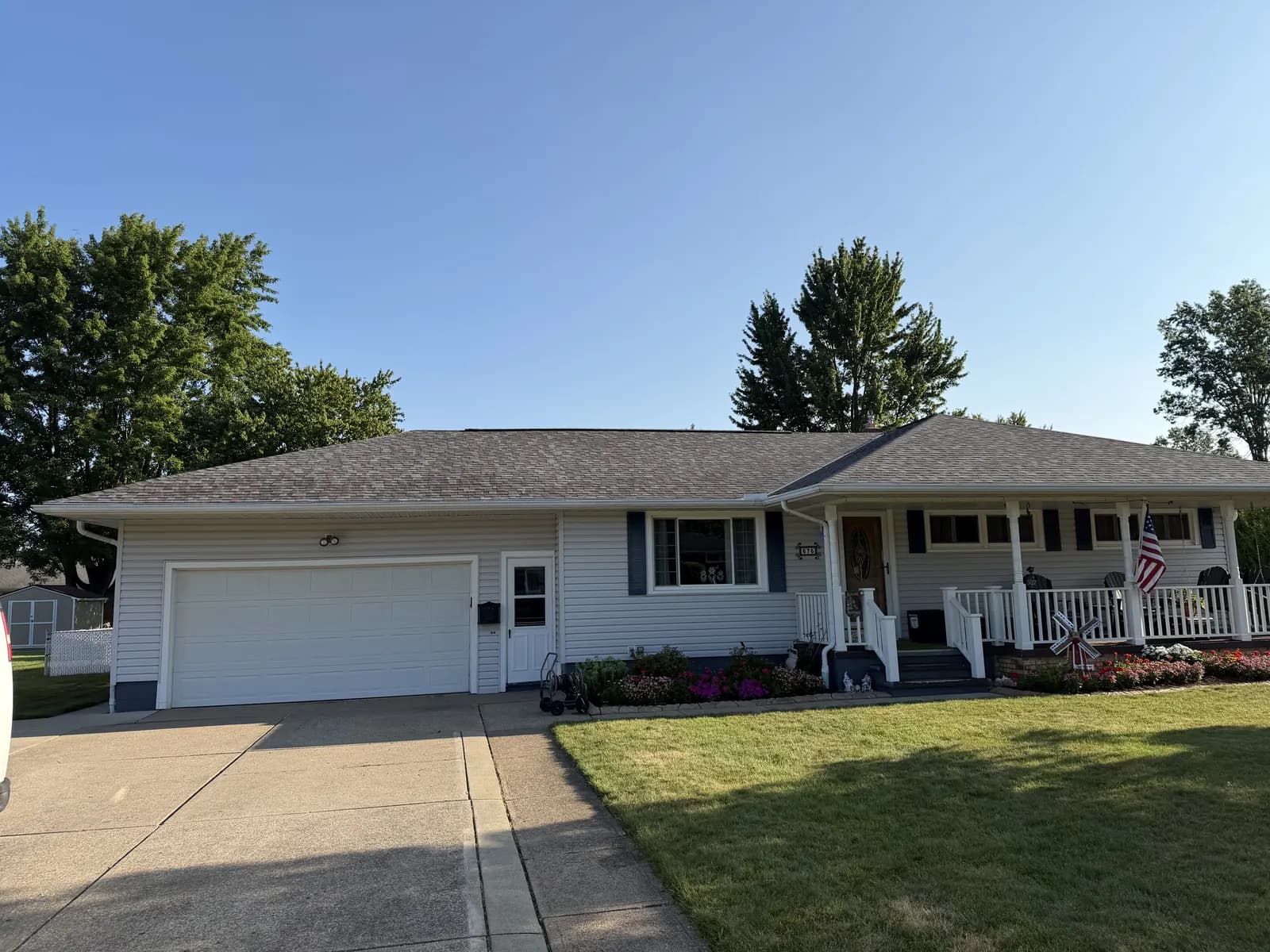 The same home with its new shingle roof finished, driveway swept and landscaping intact